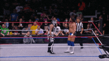 two wrestlers are standing in a ring with one wearing a mask that says ' a ' on it