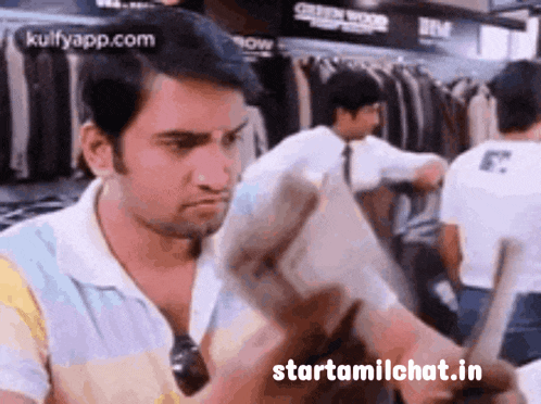 a man is reading a newspaper in a store with the website starttamilchat.in visible in the corner