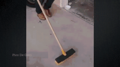 a person is using a broom to clean a concrete floor .