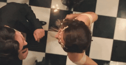 a man and a woman are standing on a checkered floor with hallmark written on the bottom right