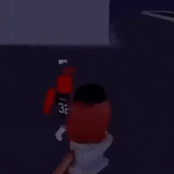 a man in a blue shirt is standing next to a red roblox character with the number 32 on his back .