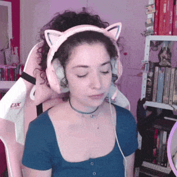 a woman wearing headphones with cat ears is sitting in a pink chair