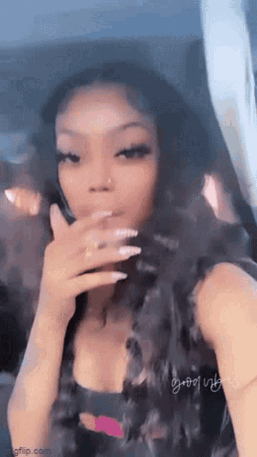 a woman is taking a selfie in a car while holding her hand to her face .