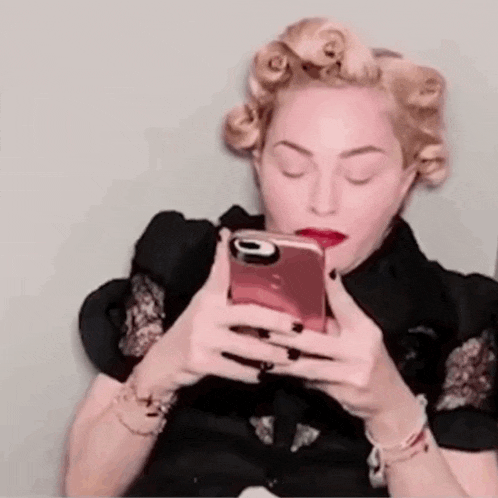 a woman with curlers in her hair is holding a cell phone in her hand .