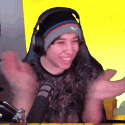 a young man wearing headphones and a beanie is sitting in front of a microphone and smiling .
