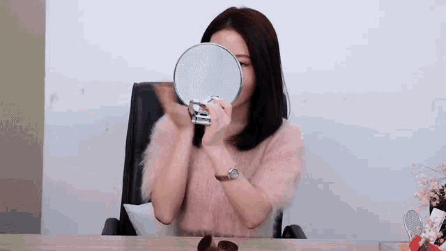 a woman is looking at herself in a mirror while wearing a watch