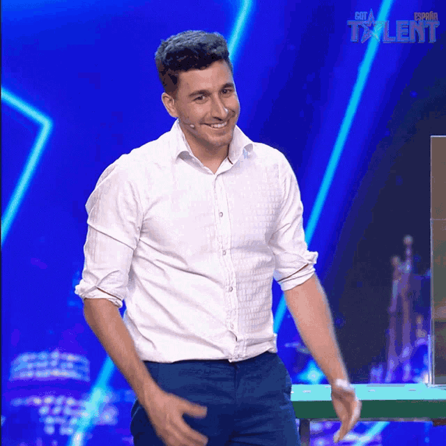 a man in a white shirt and blue pants stands on a stage in front of a sign that says talent
