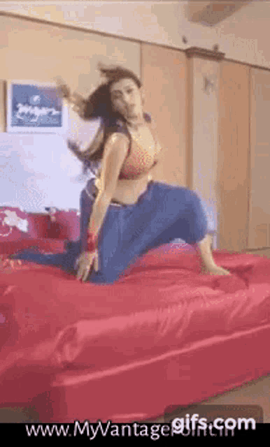 a woman is jumping on a bed with the website www.myvantagegifs.com in the corner