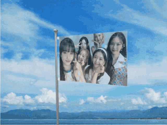 a flag with a picture of a group of girls on it against a blue sky
