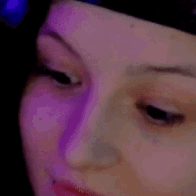 a close up of a person 's face with purple lights behind them .