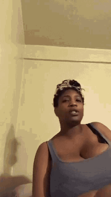 a woman with very large breasts is wearing a blue tank top and a headband .