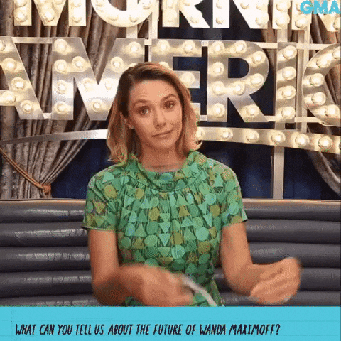 a woman in a green shirt is standing in front of a sign that says gma on it