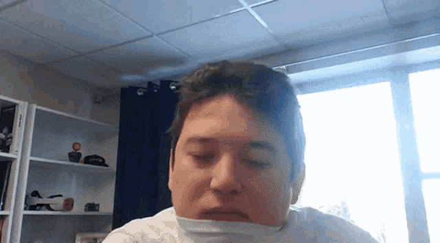 a man with his eyes closed is wearing a white shirt and a white scarf around his neck