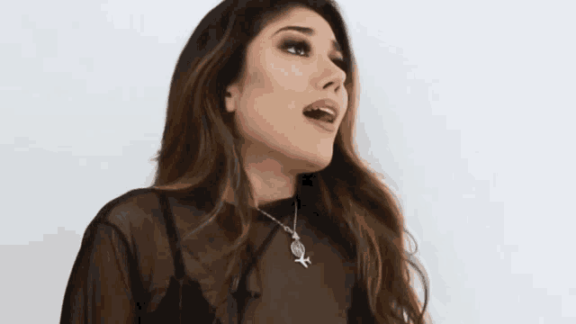 a woman wearing a black top and a necklace with an airplane on it