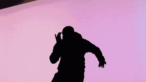a silhouette of a man is standing in front of a pink wall .
