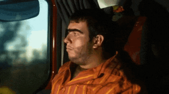 a man in an orange and yellow striped shirt is looking out of a window