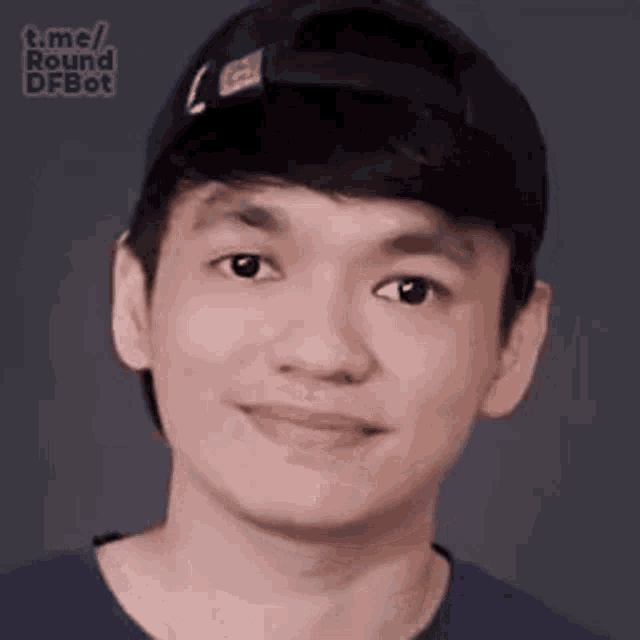 a young man wearing a baseball cap and a blue shirt is making a funny face .
