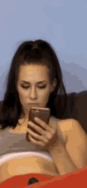 a woman is sitting on a couch holding a cell phone in her hand .