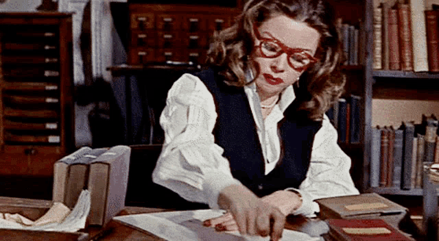 a woman wearing glasses is working at a desk