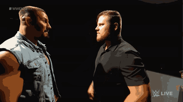 two men are facing each other in a dark room and the words wwe live are on the bottom right