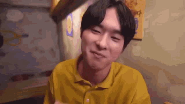 a man in a yellow shirt is sitting at a table in a restaurant .