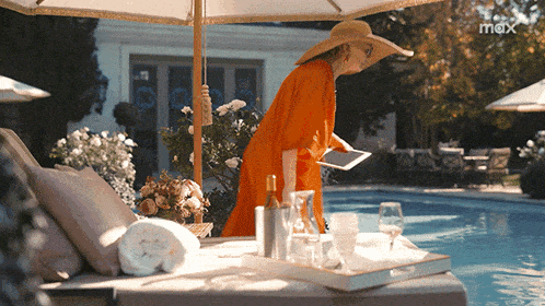 a woman standing next to a swimming pool with a max logo in the background