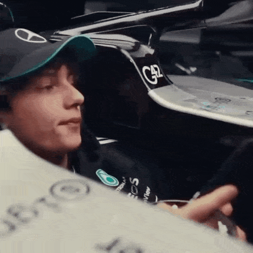 a man wearing a hat is sitting in a car and looking at his phone .