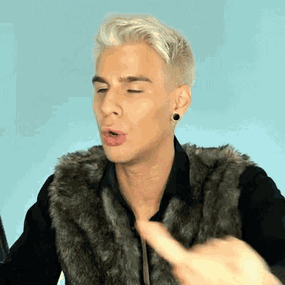a man with blonde hair wearing a fur vest and black earrings