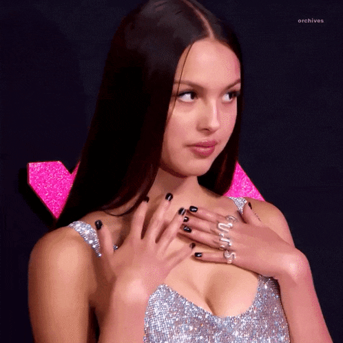 a woman wearing a silver dress with black nails and a ring that says archives