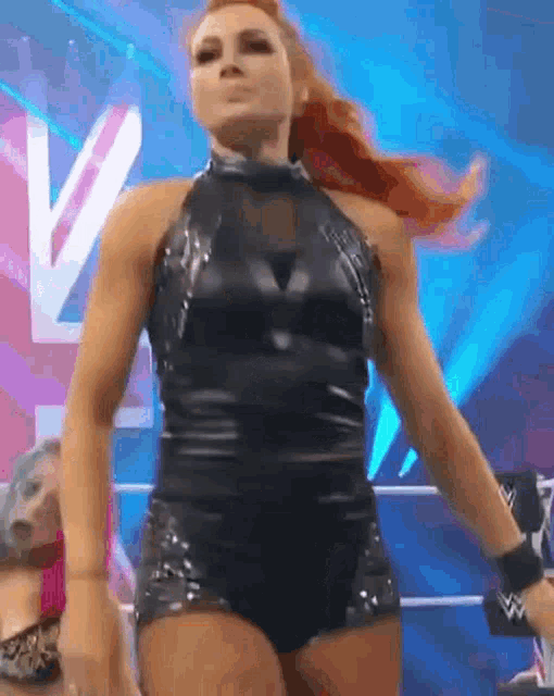 a woman is standing in a wrestling ring wearing a black bodysuit .