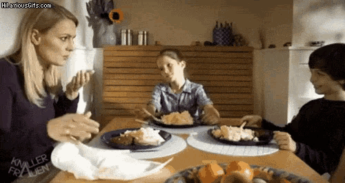 a woman and two children are sitting at a table eating dinner .