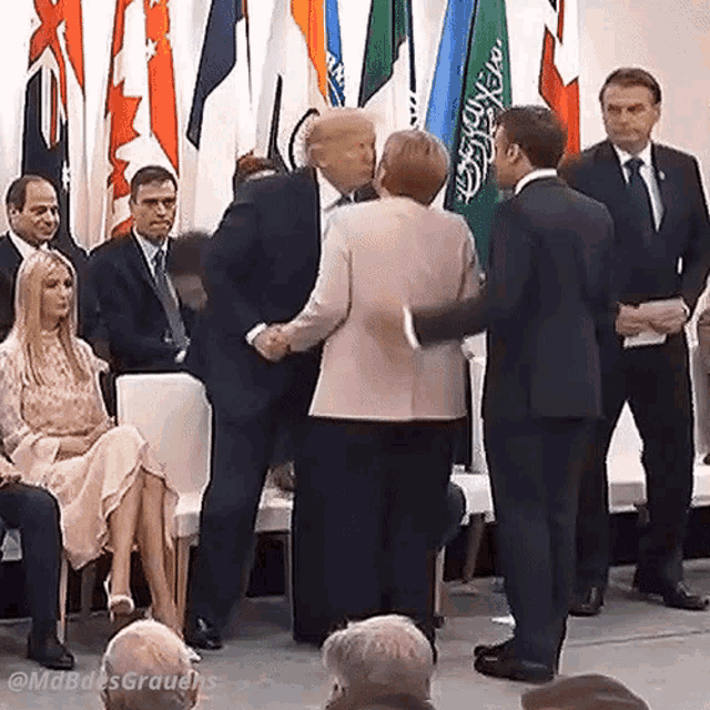 a man in a suit is shaking hands with a woman in a pink jacket in front of a crowd .