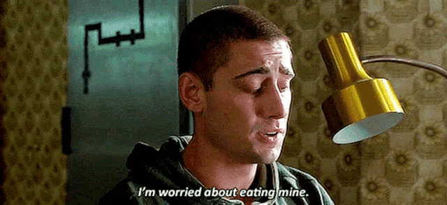 a man is sitting in front of a lamp and says `` i 'm worried about eating mine . ''