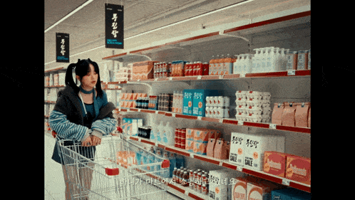 a woman pushes a shopping cart in a store with a sign that says sale on it