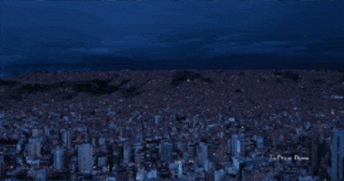 an aerial view of a city at night with a blue sky in the background