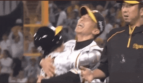 a baseball player is laughing while being carried by a man .