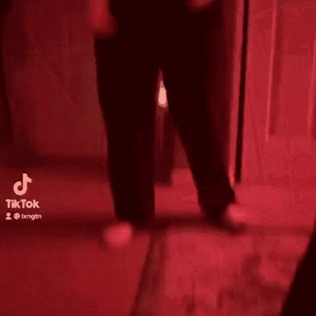 a man in a black shirt and black pants is standing in front of a door .