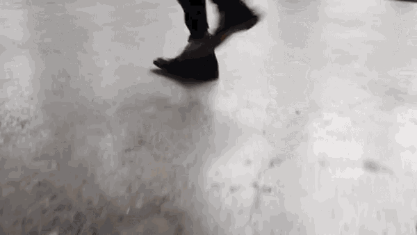 a person is walking on a concrete floor with their feet visible .