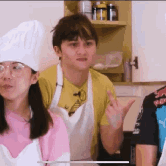 a man wearing a chef 's hat and apron is giving the middle finger to a woman .