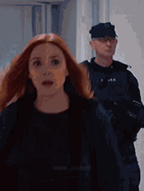 a woman with red hair is standing next to a man in a black hat
