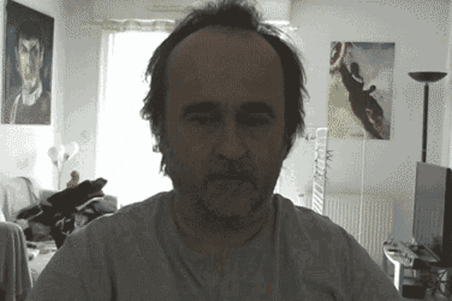 a man with a beard is looking at the camera in a room