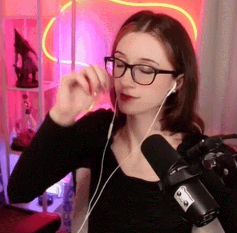 a woman wearing glasses and ear buds is talking into a microphone .