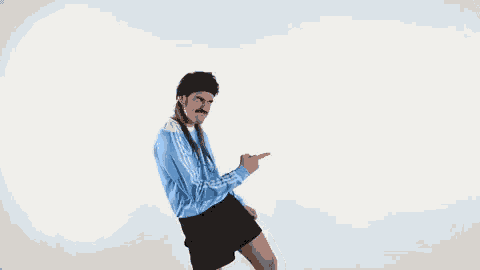 a man with long hair and a mustache is dancing in front of a white background .