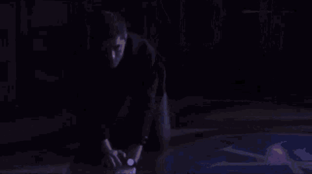 a blurry picture of two people fighting in a dark room with a purple background .