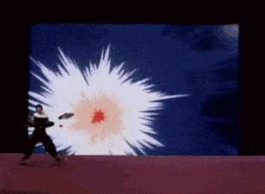 a man is standing in front of a screen with a large explosion in the background
