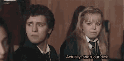 a woman in a school uniform is talking to another woman while standing in front of a wooden wall .