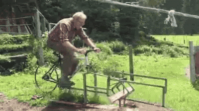 an elderly man is riding a bike on a fence in a field .