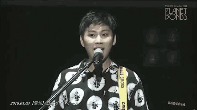 a man singing into a microphone with planet bomb written on the bottom right