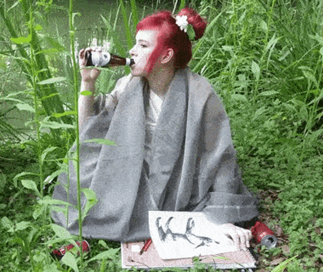 a woman drinking from a bottle with the letter k on a piece of paper in front of her