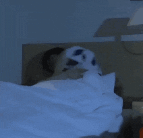 a bed with a blue blanket and a lamp on it